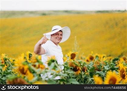 Portrait of a handsome young man in a white woman&rsquo;s hat in a field with sunflowers. Man is having fun outdoors. copy space. selective focus.. Portrait of a handsome young man in a white woman&rsquo;s hat in a field with sunflowers. Man is having fun outdoors. copy space. selective focus