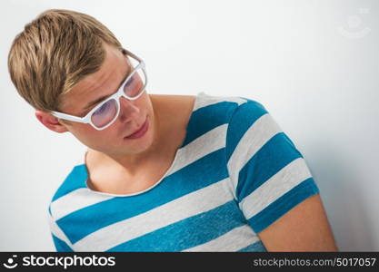 Portrait of a handsome young man in glasses posing leaning on the wall