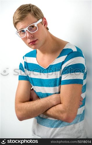 Portrait of a handsome young man in glasses posing leaning on the wall