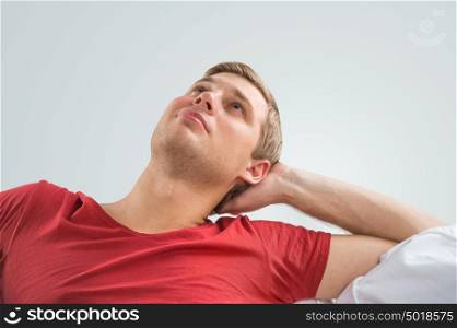 Portrait of a handsome young man looking upwards while relaxing and dreaming at home