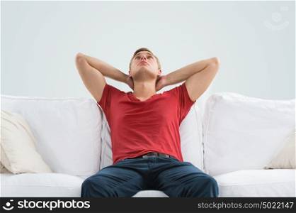 Portrait of a handsome young man looking upwards while relaxing and dreaming at home