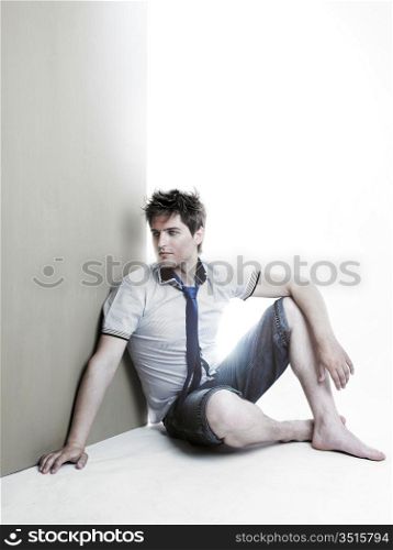 Portrait of a handsome young man sitting against the wall