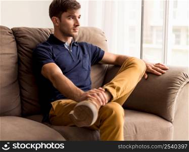 Portrait of a handsome young man sitting on the sofa