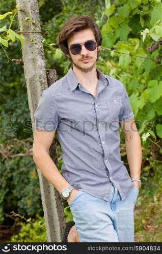 portrait of a handsome young man wearing sunglasses and enjoying the nature