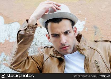Portrait of a handsome young man with a hat in urban background