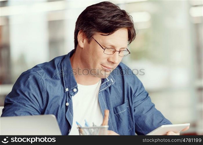 Portrait of a handsome young man working with a tablet in an office