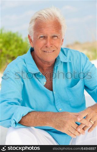 Portrait of a happy attractive handsome senior man sitting down outside on a beach and smiling. Portrait of Attractive Handsome Senior Man on Beach