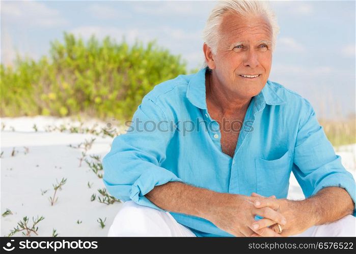 Portrait of a happy attractive thoughtful handsome senior man sitting down outside on a beach and smiling. Portrait of Attractive Handsome Senior Man on Beach
