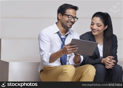 Portrait of a happy beautiful corporate couple together watching digital tablet