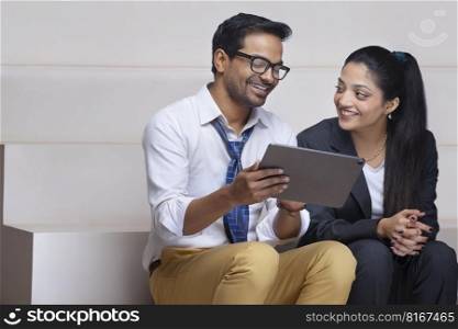 Portrait of a happy beautiful corporate couple together watching digital tablet