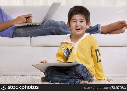 Portrait of a happy boy drawing with father in the background