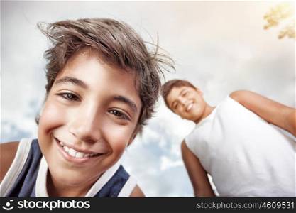 Portrait of a happy boys smiling to camera and having fun, over grey sky background, allow oneself to enjoy the pleasure of freedom in a summer camp