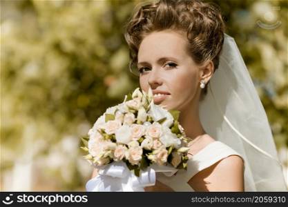 portrait of a happy bride holding flowers in the park. happy bride