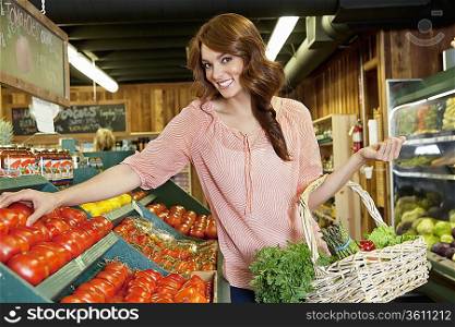 Portrait of a happy brunette shopping for tomatoes in supermarket