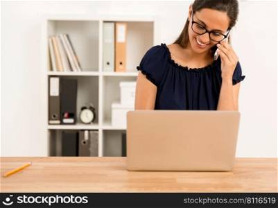 Portrait of a happy businesswoman sitting at her desk and talking at phone