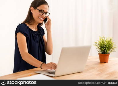 Portrait of a happy businesswoman sitting at her desk and talking at phone