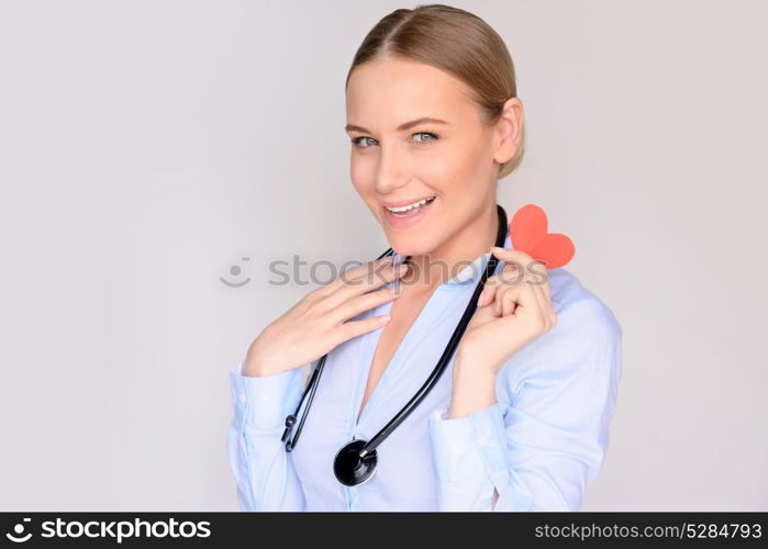 Portrait of a happy cardiologist doctor with conceptual paper heart in hands, successful treatment, good medical specialist, healthy life concept