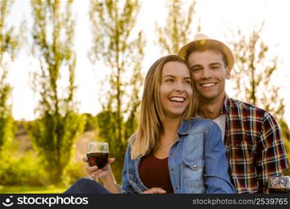 Portrait of a happy couple enjoying a day in the park together and drinking wine
