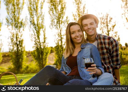 Portrait of a happy couple enjoying a day in the park together and drinking wine