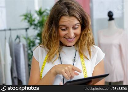 portrait of a happy dressmaker using a tablet