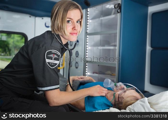 Portrait of a happy EMT worker inside ambulance tending to senior woman patient