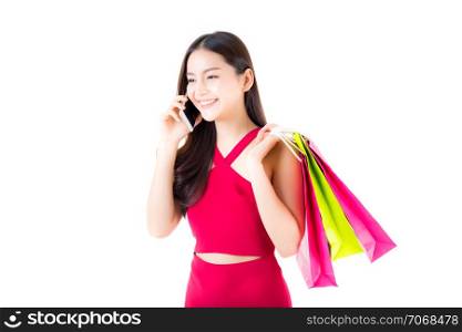 portrait of a happy excited asian woman in red dress standing talking phone and holding colorful shopping bags with happy isolated on a white background.