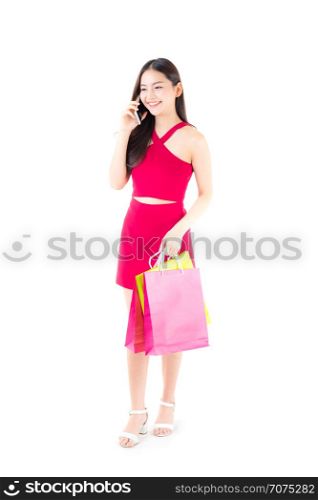 portrait of a happy excited asian woman in red dress standing talking phone and holding colorful shopping bags with happy isolated on a white background.
