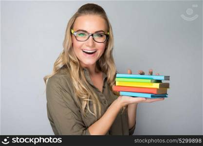 Portrait of a happy excited student girl wearing glasses over gray background, taking books for new educational season, enjoying education in the university