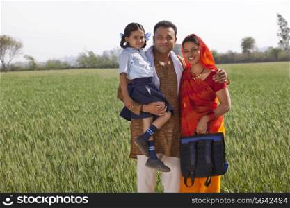 Portrait of a happy family of three standing together with field in background