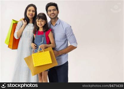 PORTRAIT OF A HAPPY FAMILY POSING WITH SHOPPING BAGS IN HAND