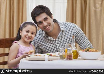 Portrait of a happy father and daughter having pizza at restaurant