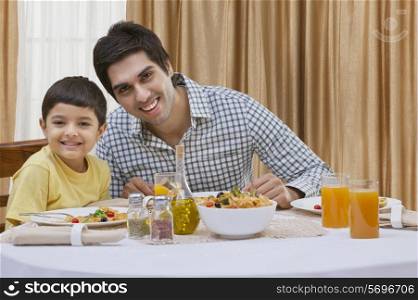 Portrait of a happy father and son having pizza at table