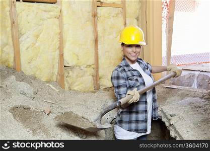 Portrait of a happy female contractor digging sand at construction site