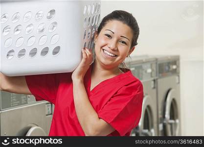 Portrait of a happy female employee carrying laundry basket