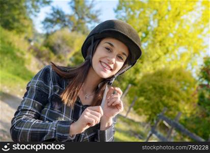 Portrait of a happy female jockey with an helmet