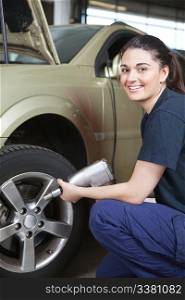 Portrait of a happy female mechanic changing a tire in a shop