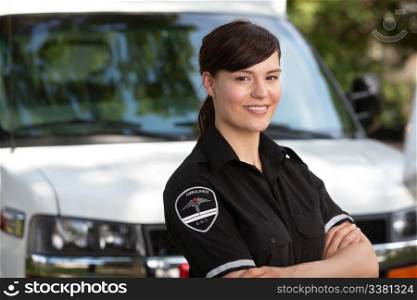 Portrait of a happy friendly female paramedic standing in front of ambulance
