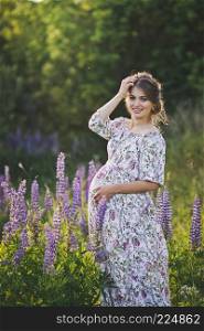 Portrait of a happy future mother against the background of Lupin field.. Portrait in full growth of the girl on the background of the field of lupine