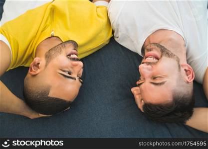 Portrait of a happy gay couple spending time and laying down on the floor. Lgbt and love concept.