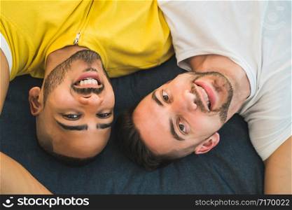 Portrait of a happy gay couple spending time and laying down on the floor. Lgbt and love concept.