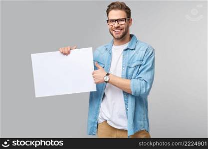 Portrait of a happy handsome young man holding blank white card or sign over white background.. Portrait of a happy handsome young man holding blank white card or sign over white background