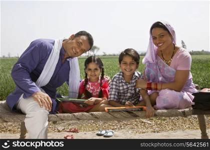 Portrait of a happy Indian family sitting on cot