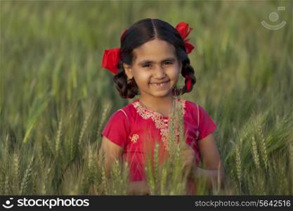 Portrait of a happy Indian girl holding wheat stalks