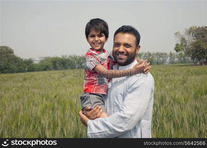 Portrait of a happy man carrying his son with wheat field in background