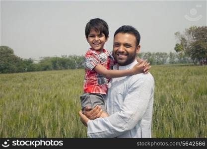 Portrait of a happy man carrying his son with wheat field in background