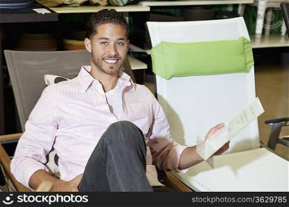 Portrait of a happy man sitting on chair in store