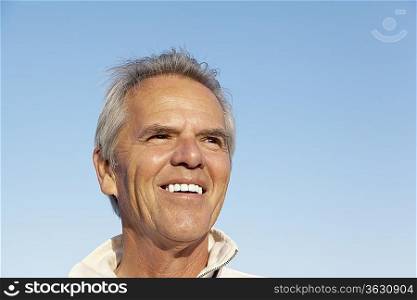 Portrait of a happy mature man over blue sky