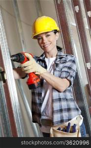 Portrait of a happy mid adult woman worker drilling at construction site