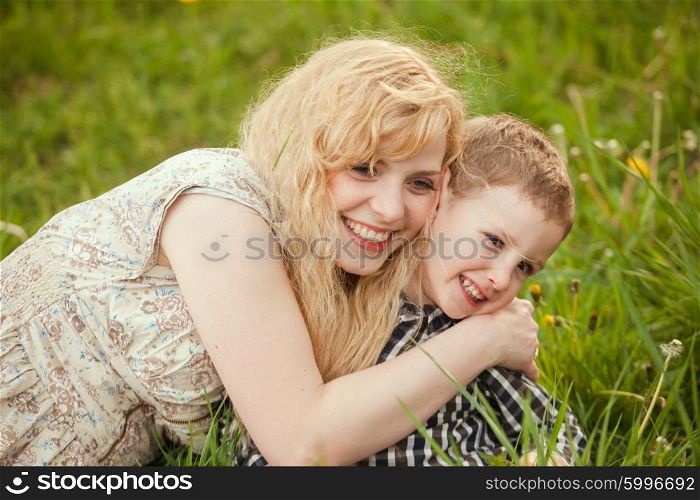 Portrait of a happy mother hugging her little son on the grass