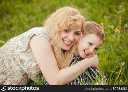 Portrait of a happy mother hugging her little son on the grass